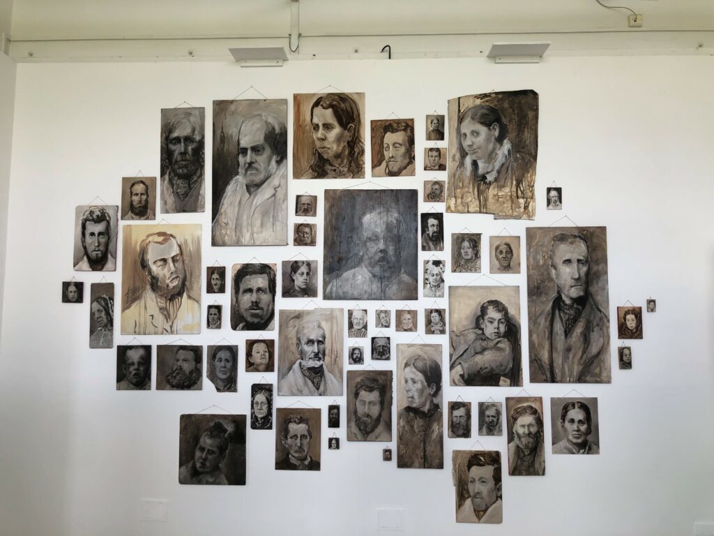 A wall of painted portraits of different sizes